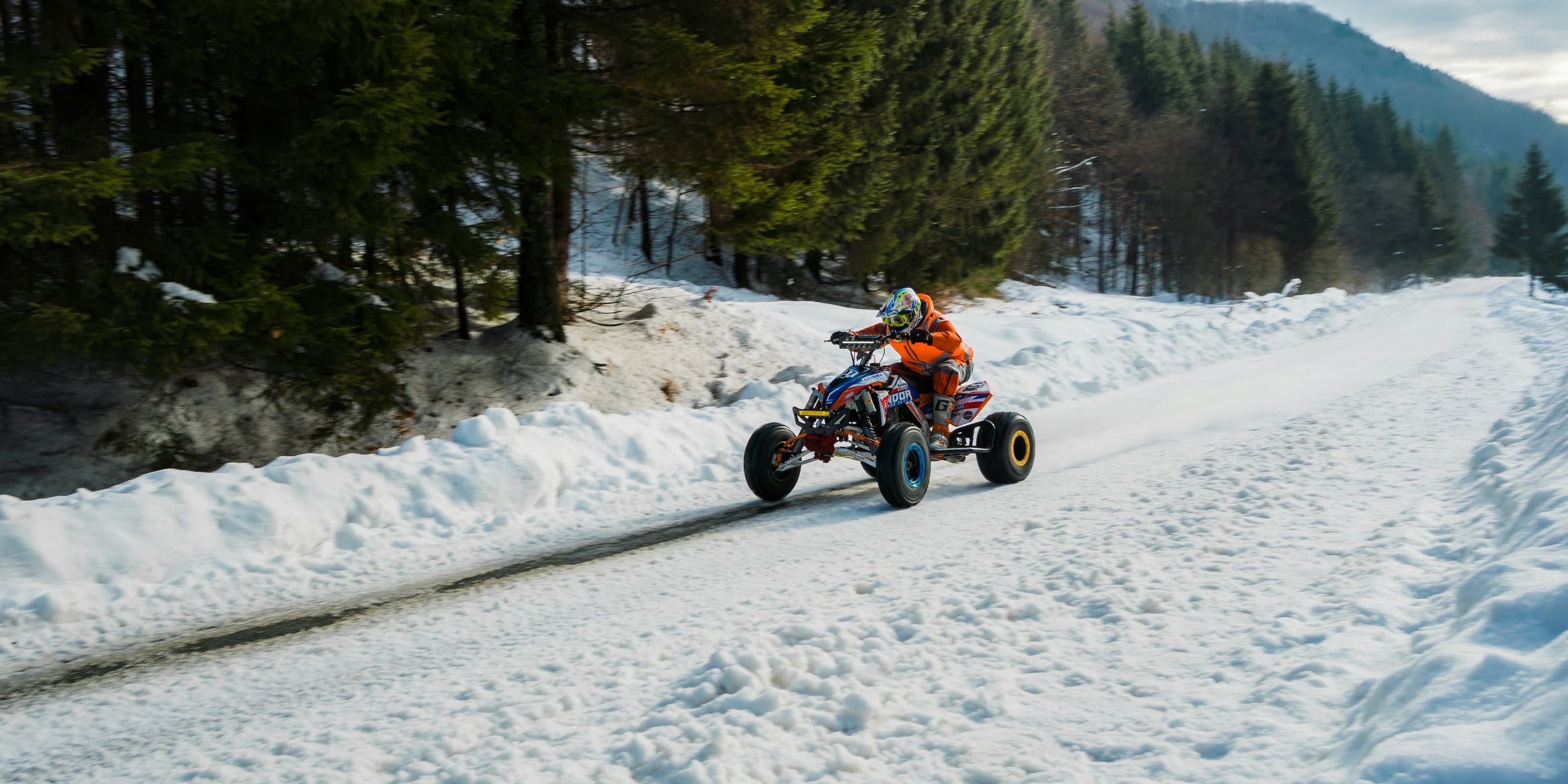 A rider on an ATV on a snowy forest trail